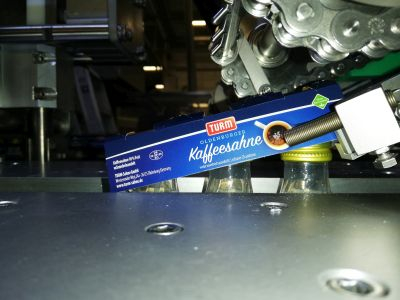 Fertig verleimter Clip wird auf die Flaschen übergeben